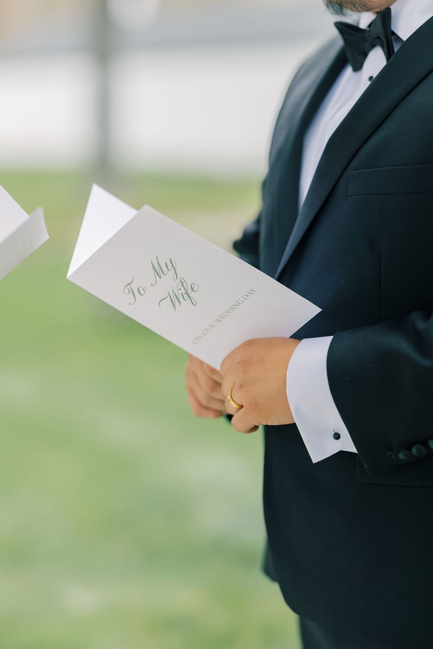 Close-up of hands holding wedding vows or letters in formal attire.