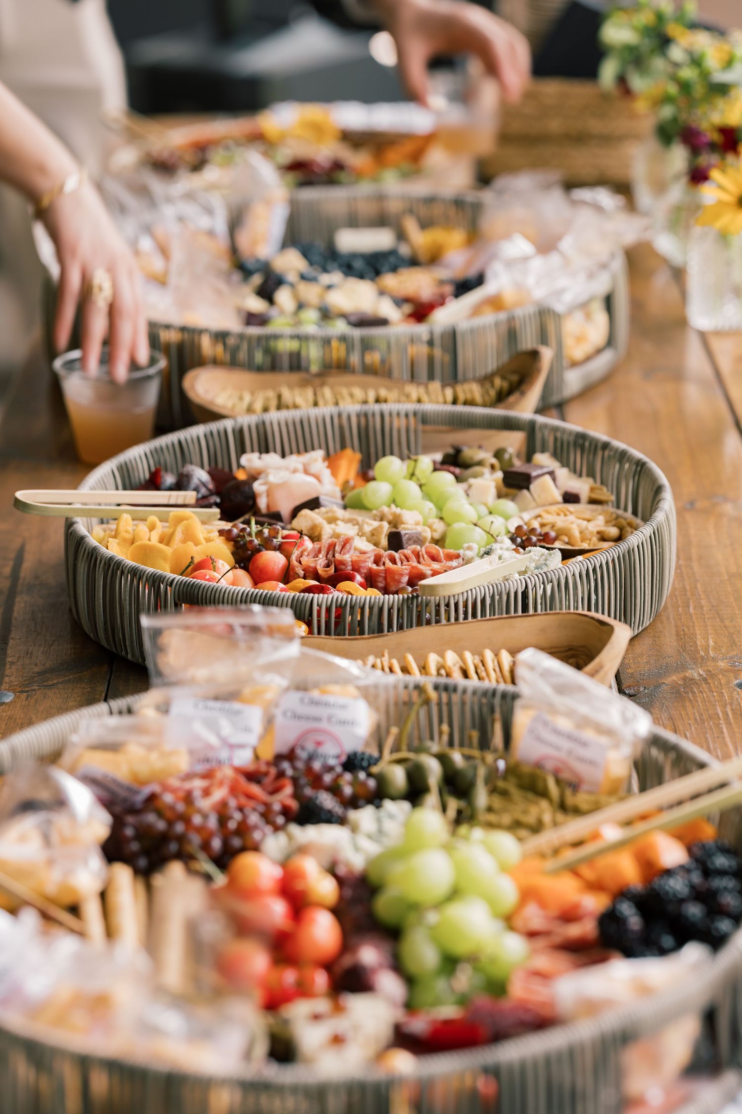 Elegant charcuterie and fruit platters arranged on wooden tables with assorted meats, cheeses, and fresh produce.