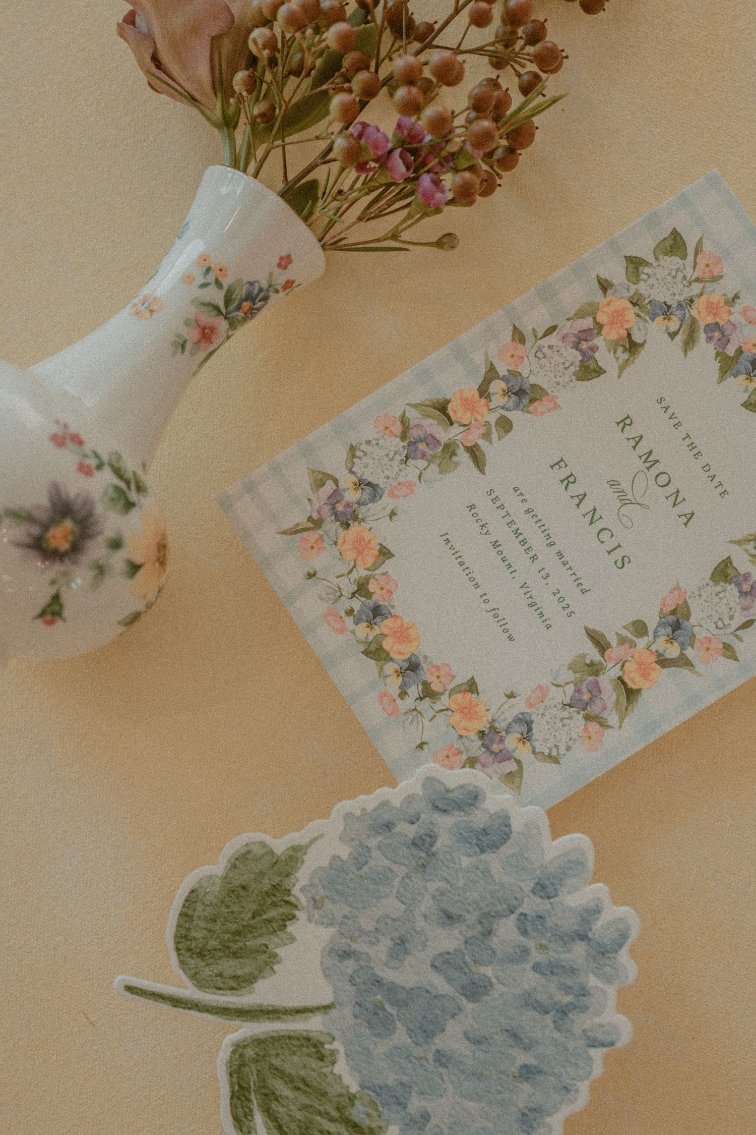 Delicate floral invitation cards with soft blue hydrangea designs and vintage-style text on a beige background.