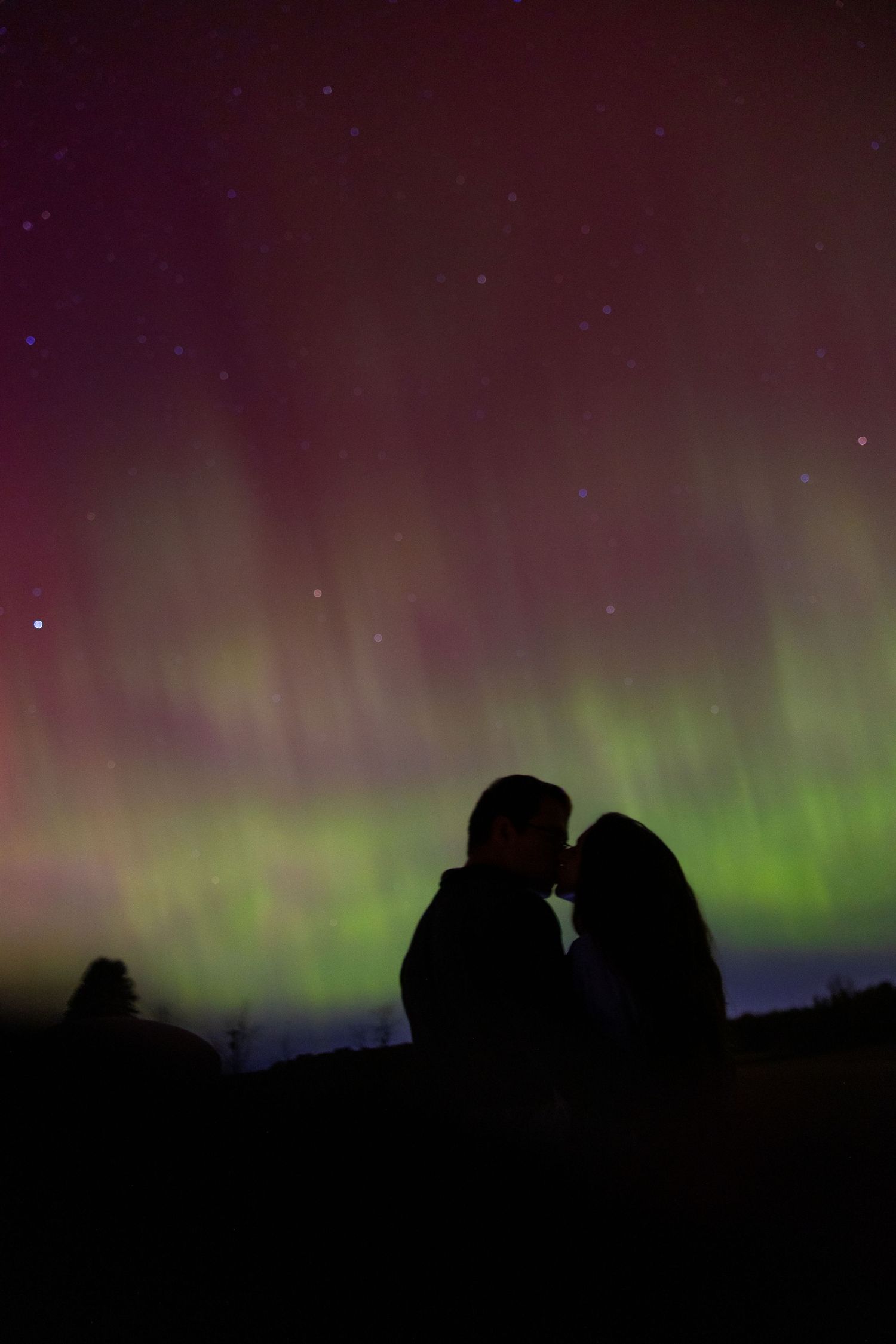 Time-lapse sequence showing green aurora borealis dancing in night sky above dark silhouetted landscape.