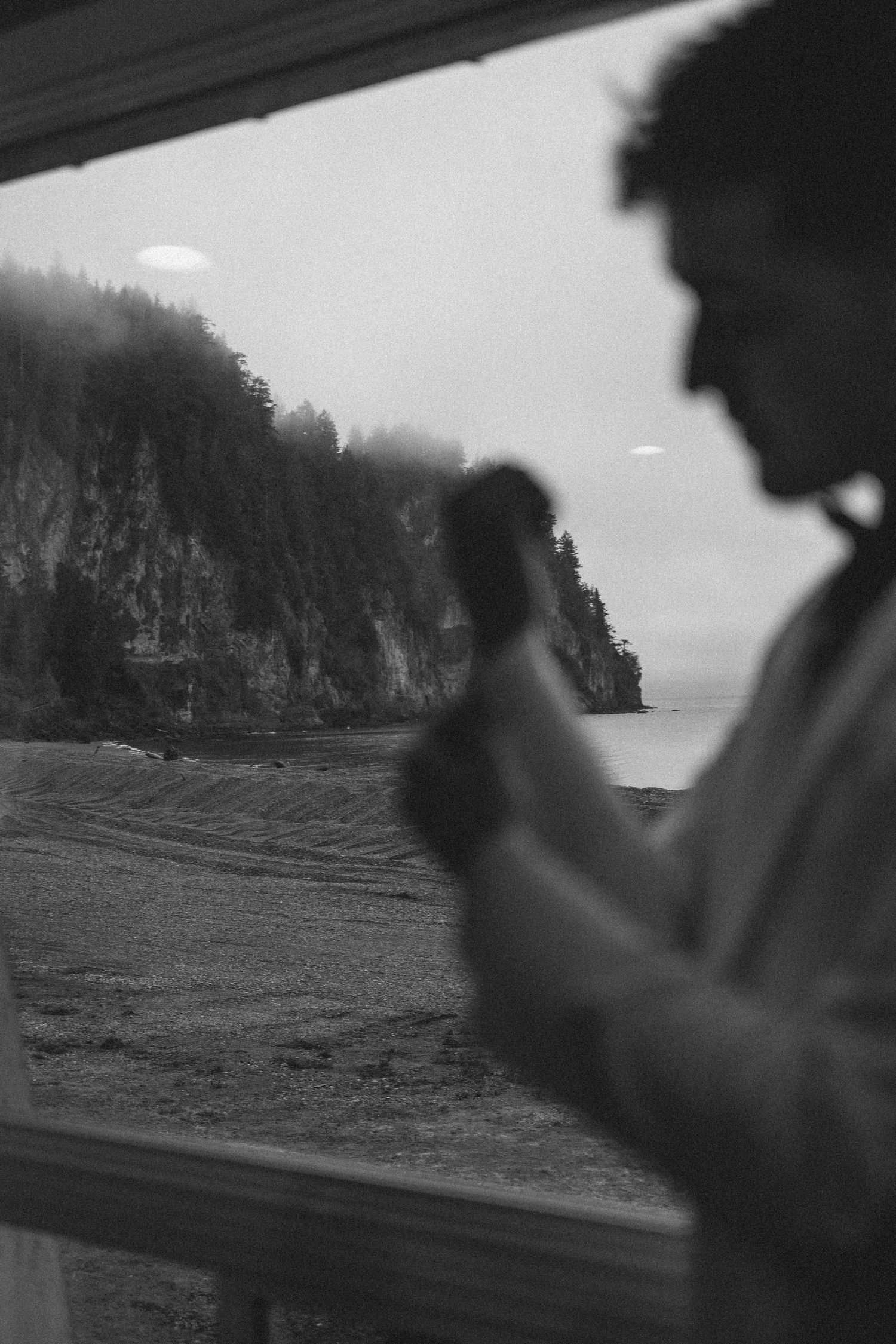 Black and white landscape view of coastal cliffs and water through a window.