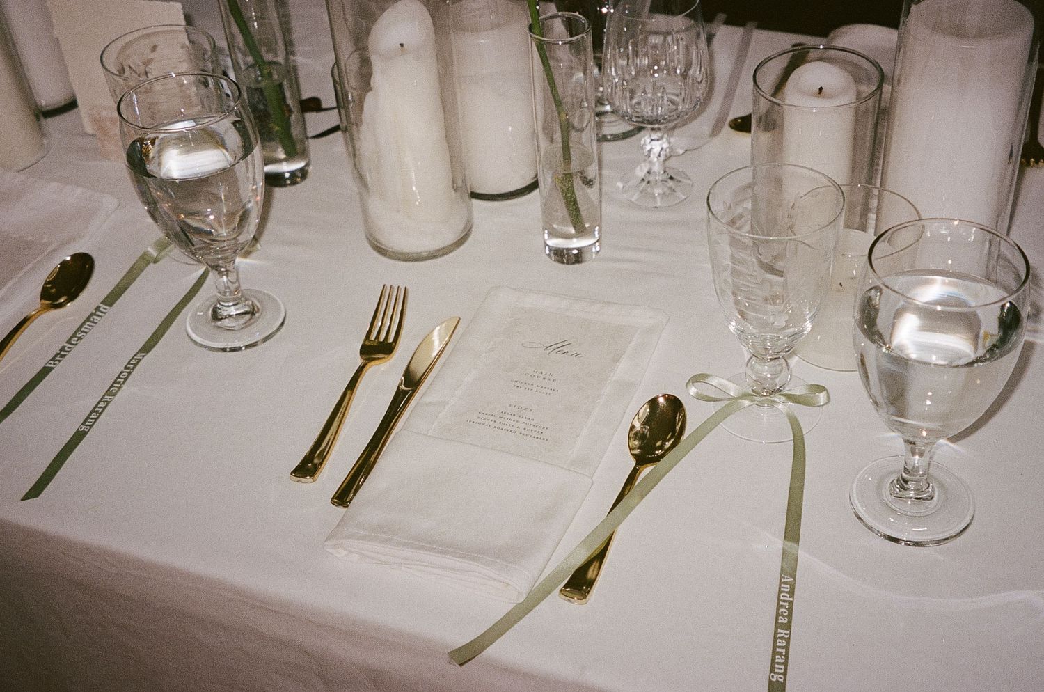 Elegant table setting with wine glasses and silverware on white tablecloth.