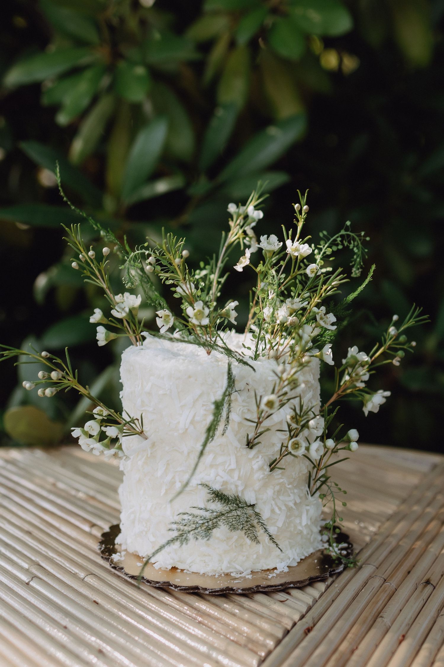 White wedding cake decorated with delicate white flowers and greenery.