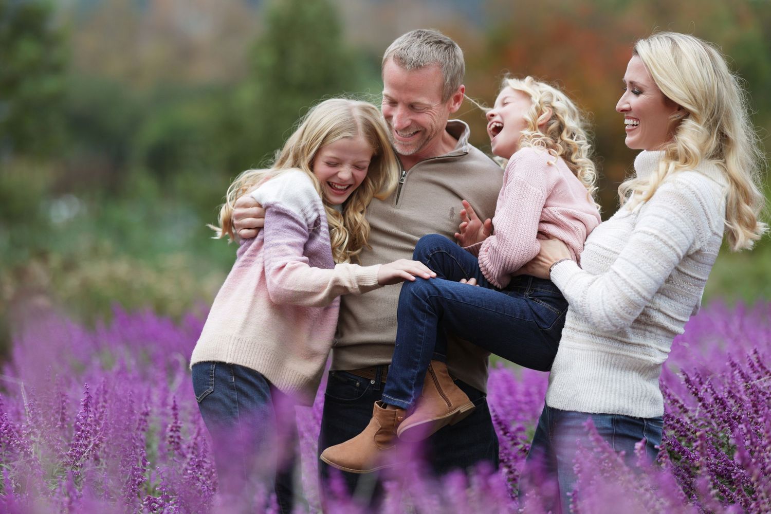 Happy family with two girls laughing in a vibrant purple lavender field during autumn.