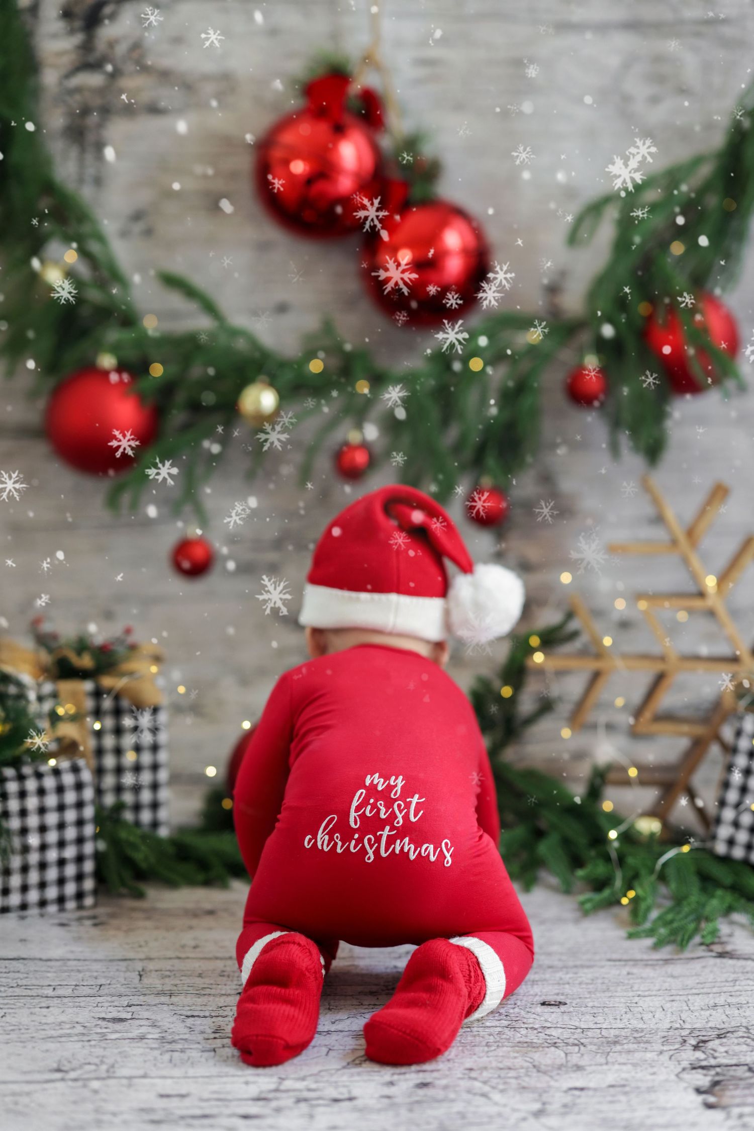 Baby in red Santa outfit crawling toward Christmas decorations with snowflake overlay effect.