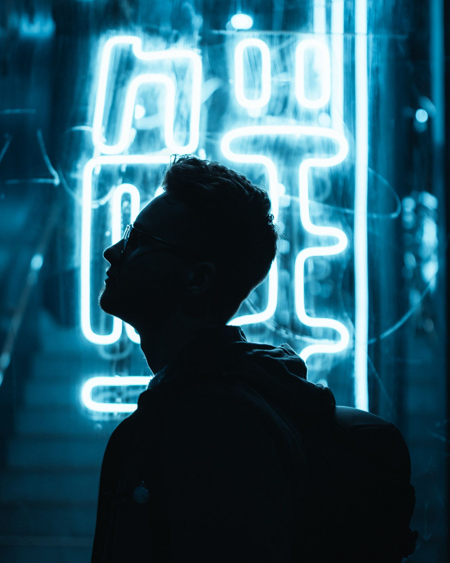 Silhouette against bright blue neon lights in an urban nighttime setting.