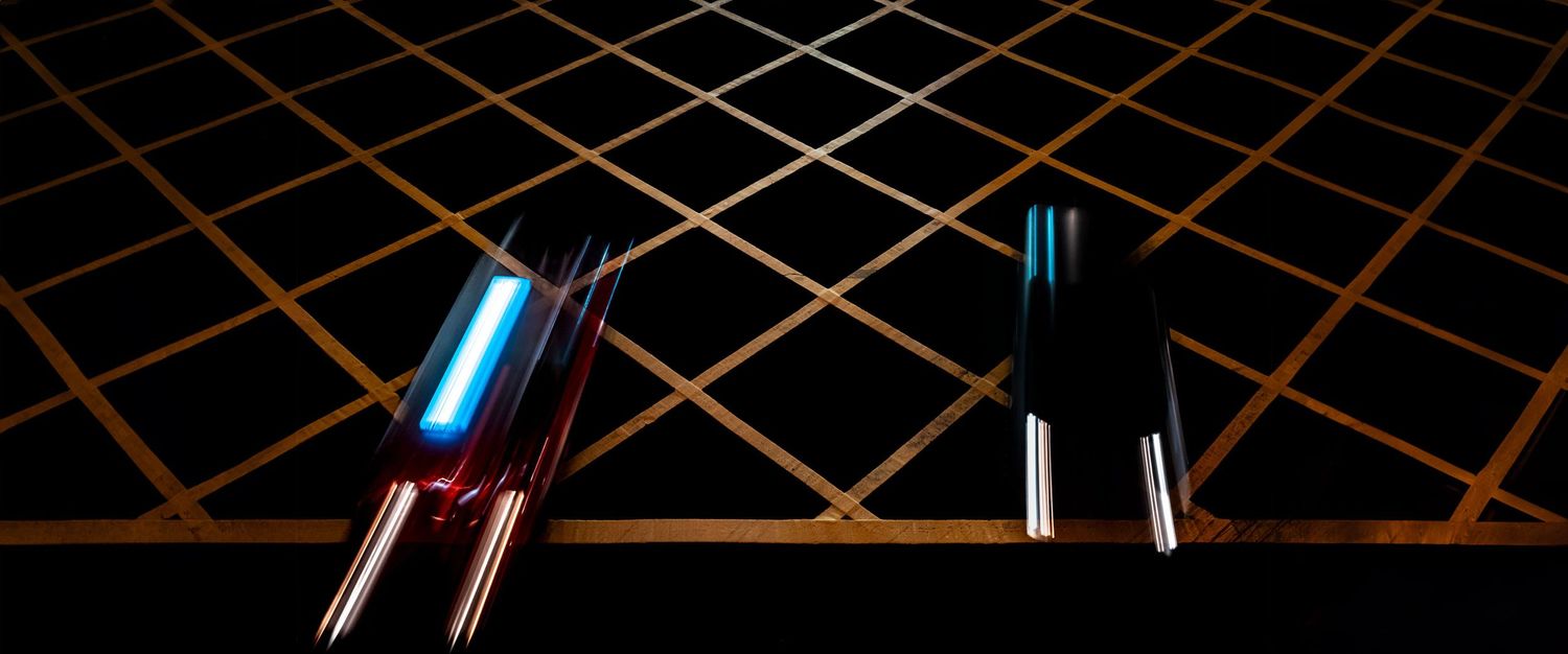 Two glowing blue light tubes against a dark geometric grid pattern background.