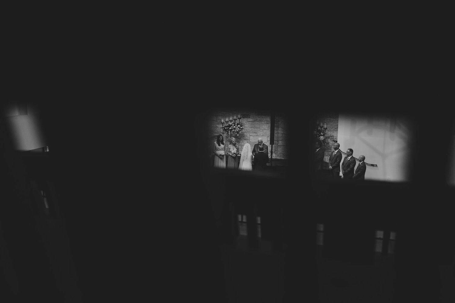 Wedding ceremony captured in dramatic dark lighting with spotlit altar.