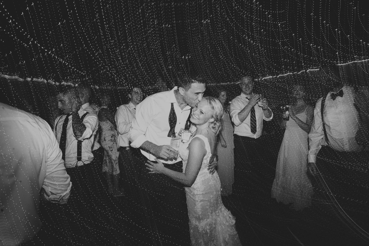 Bride and groom share a romantic first dance surrounded by guests at their wedding reception.
