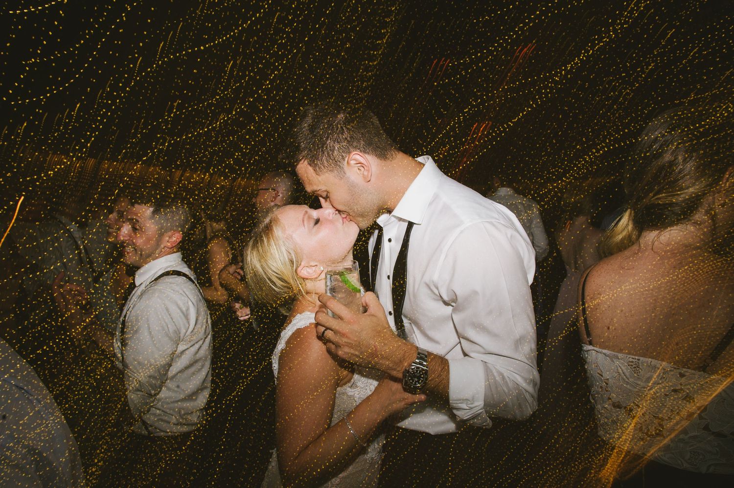 Bride and groom share a passionate kiss on the wedding reception dance floor.