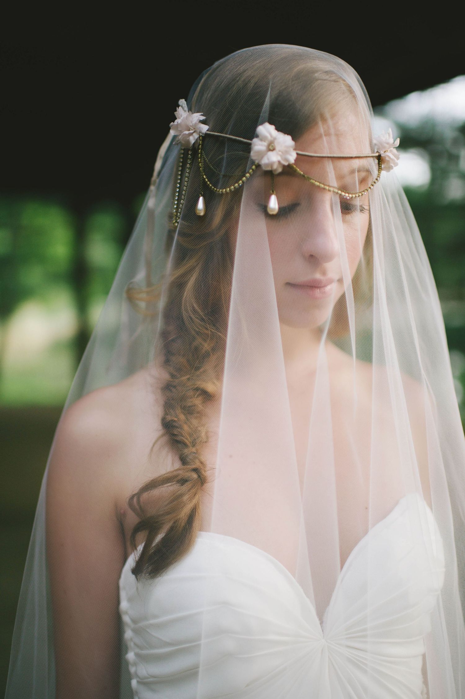 Close-up portrait of bride wearing ornate gold headpiece with floral veil and braided hair.