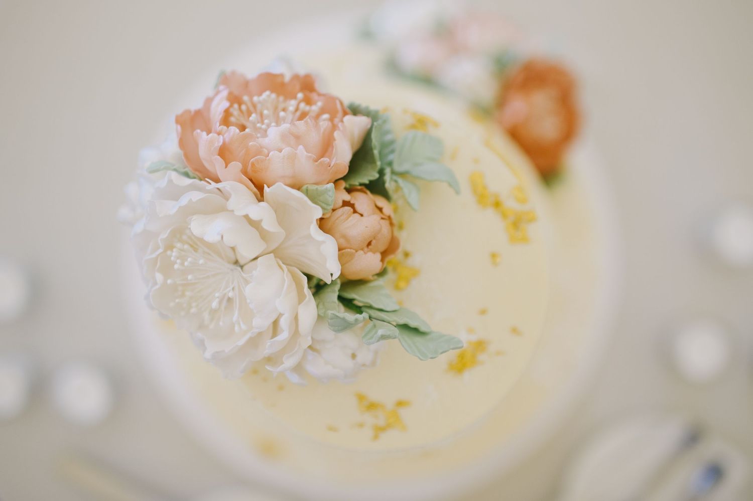 Elegant white wedding cake decorated with hand-painted pastel peony sugar flowers.