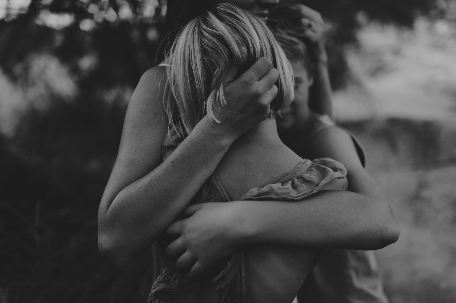 Intimate black and white close-up of two people sharing a warm emotional embrace outdoors.