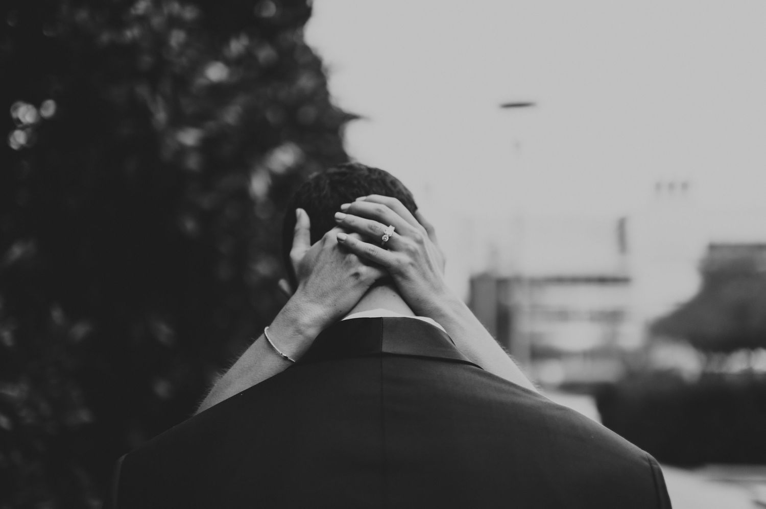 Black and white photo of a bride placing her hands on the back of a groom's head.