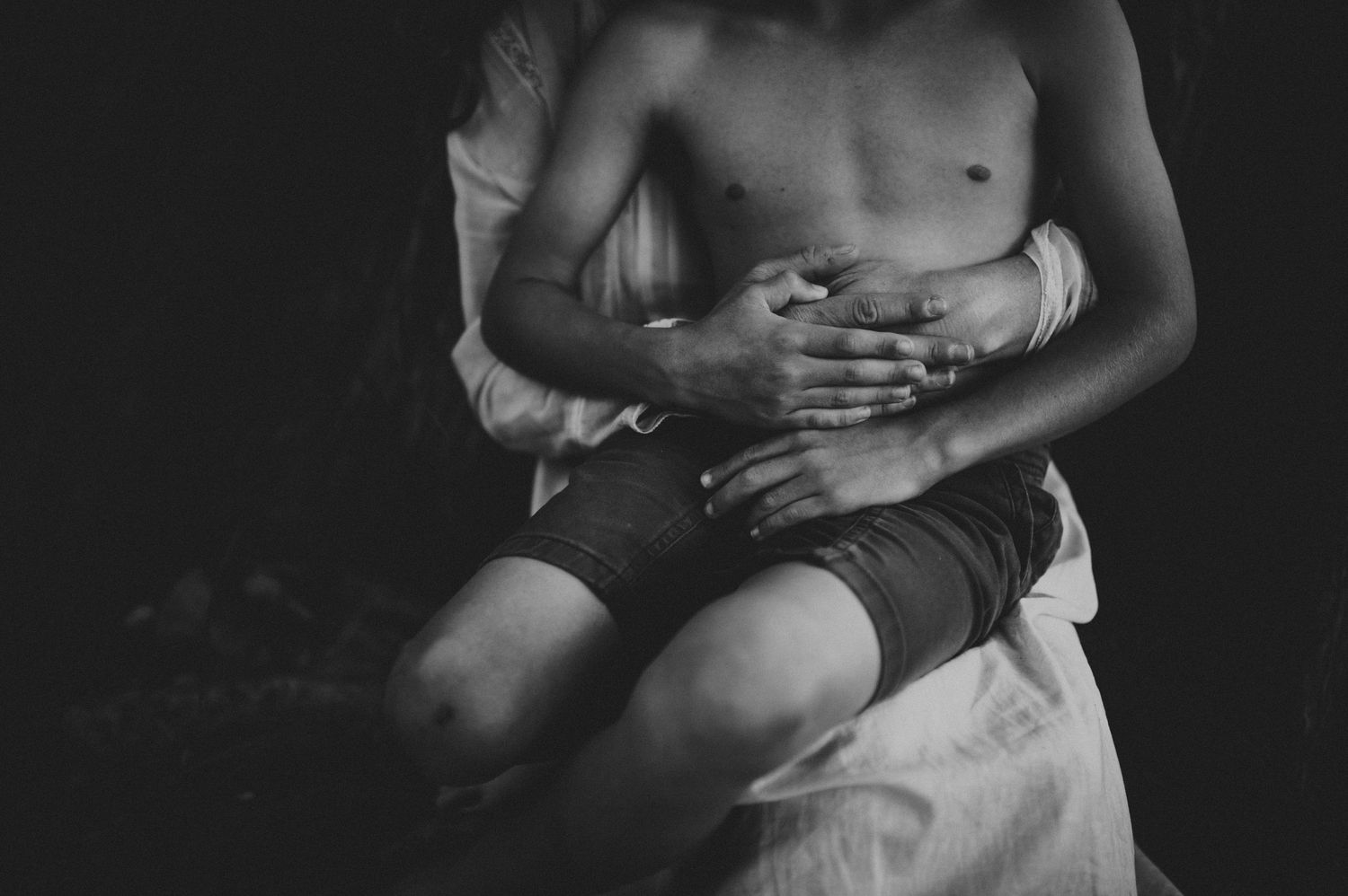 Black and white photo of a child sitting on an adults lap outdoors in an intimate family moment.