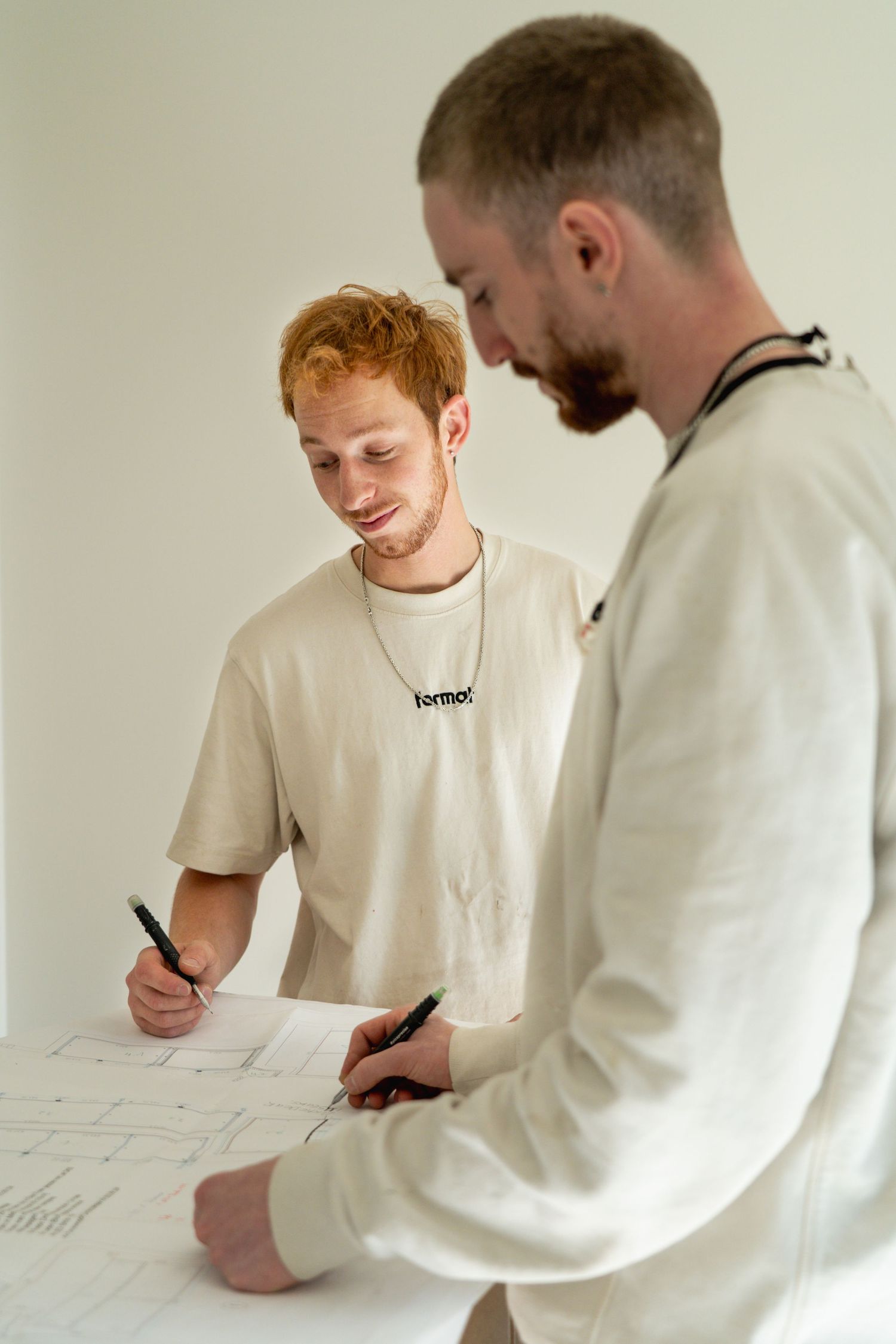 Twee mannen in witte kleding overleggen over documenten, branding fotoshoot Format Massimo door Eva Berendse
