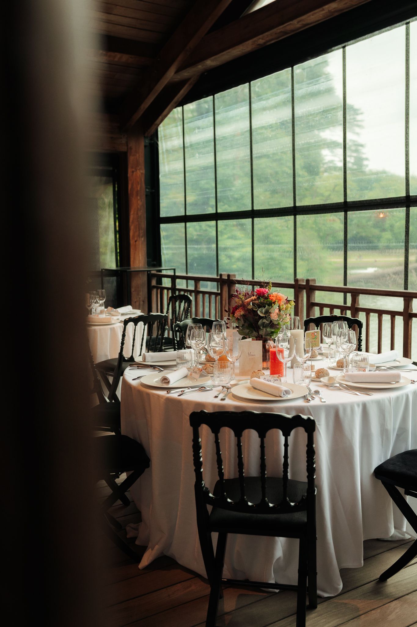 Elegant wedding reception table set with white linens near large windows.