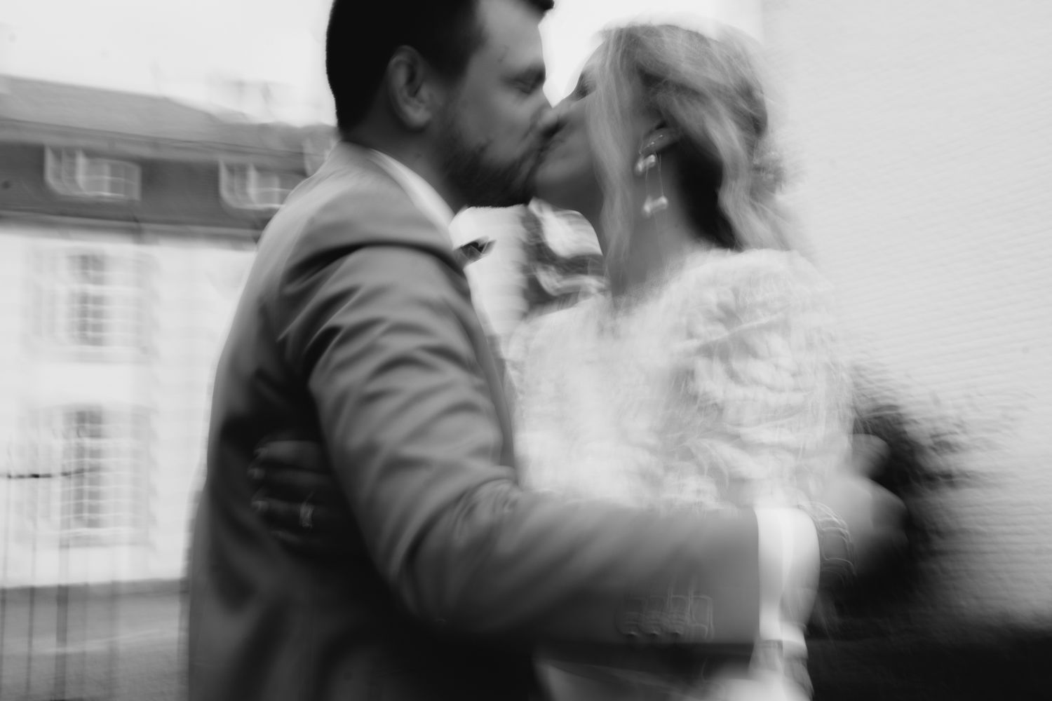 Black and white blurred artistic photo of bride and groom sharing a kiss.