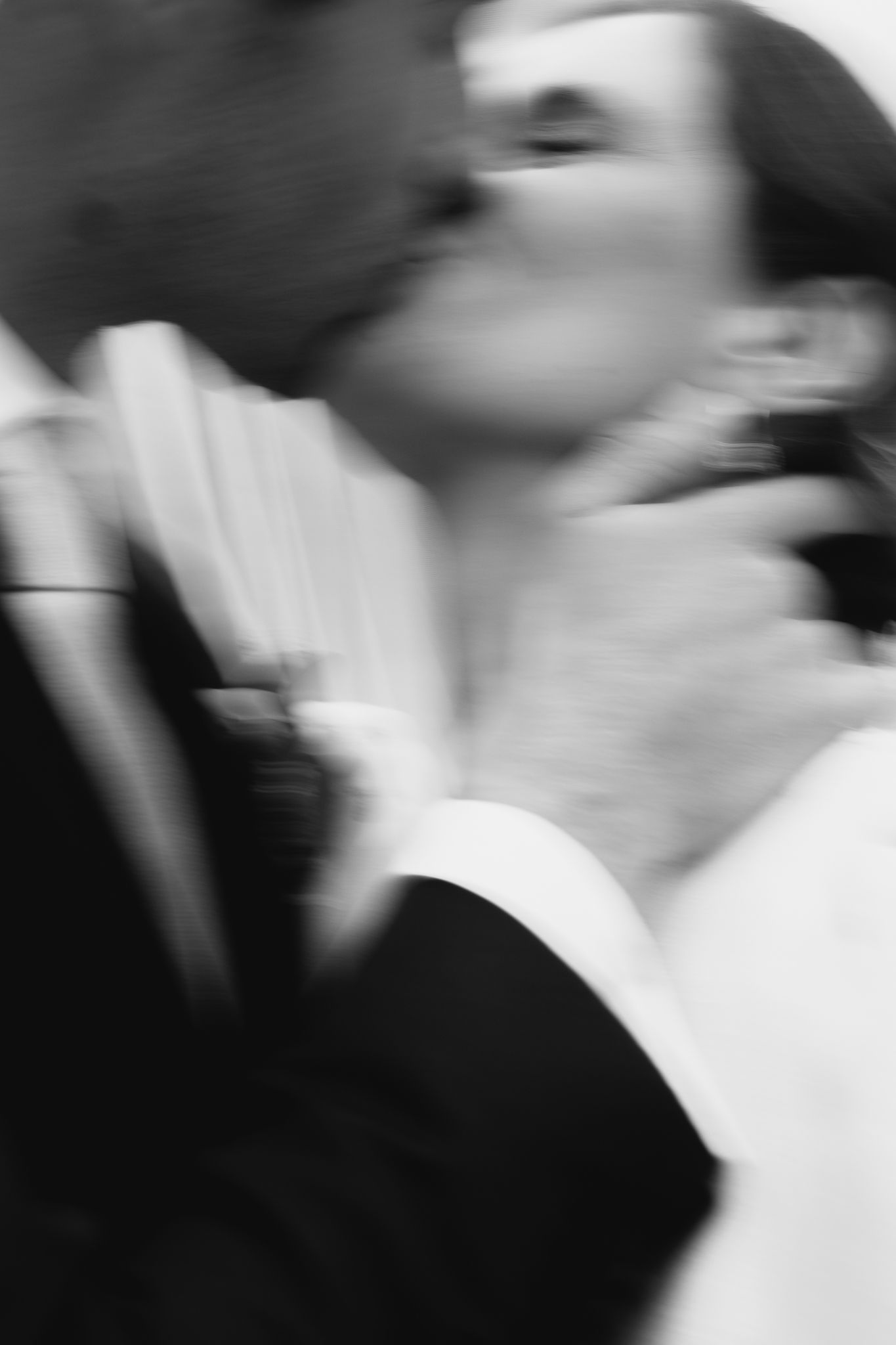 Artistic blurred black and white photo of bride and groom sharing a romantic wedding kiss.