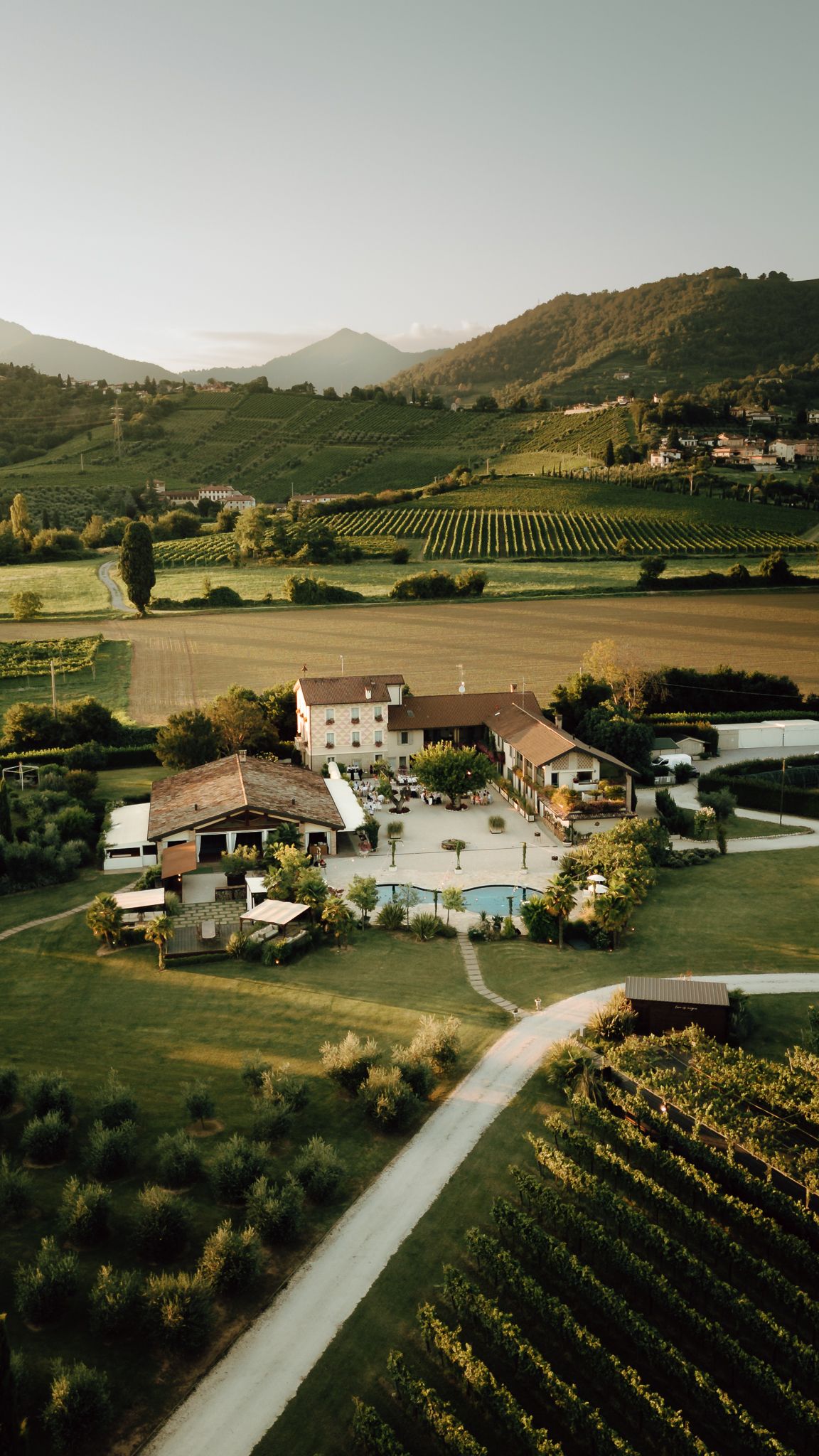 Aerial drone view of rustic vineyard wedding estate surrounded by green hills.
