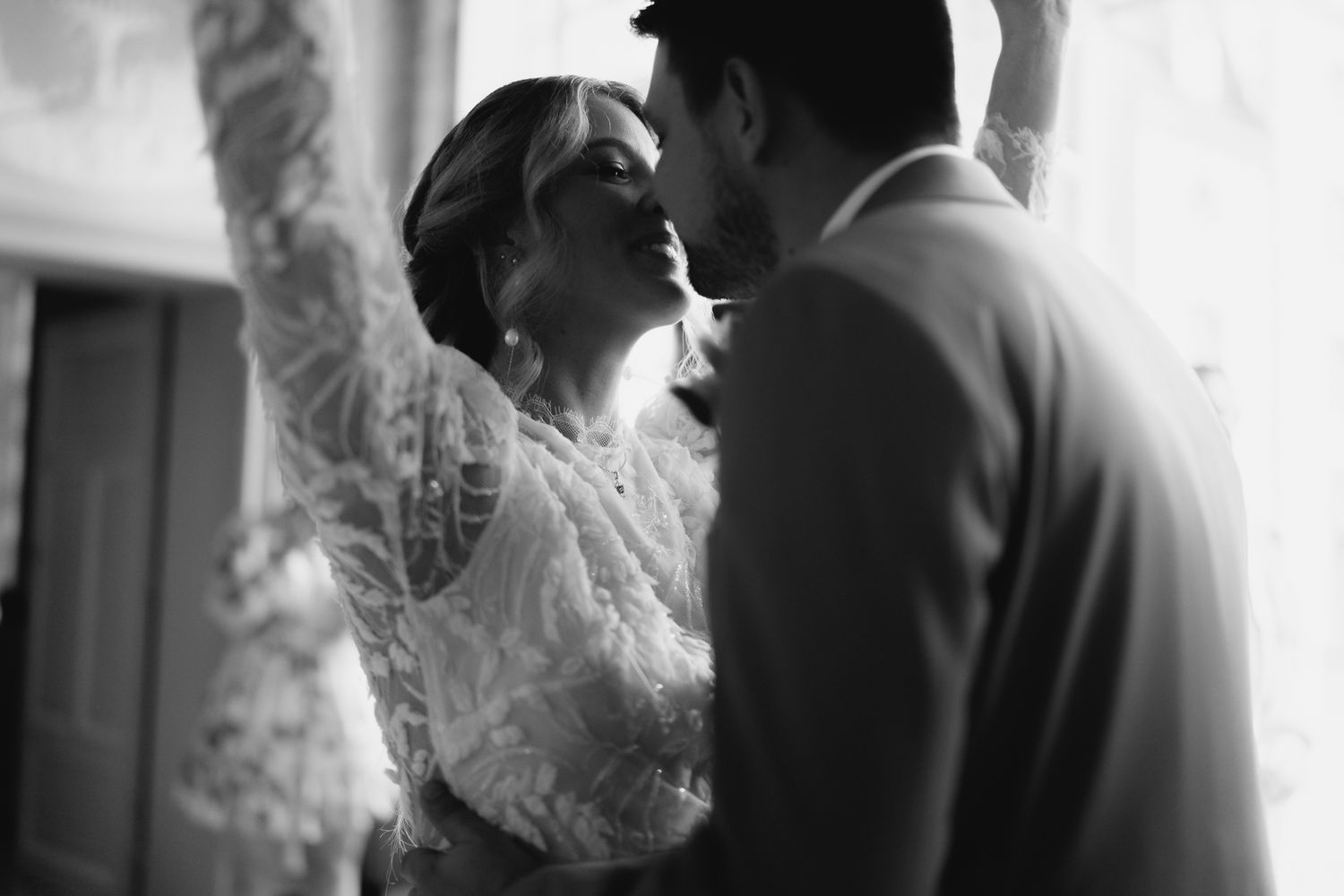 Black and white romantic photo of bride and groom almost kissing in soft light.