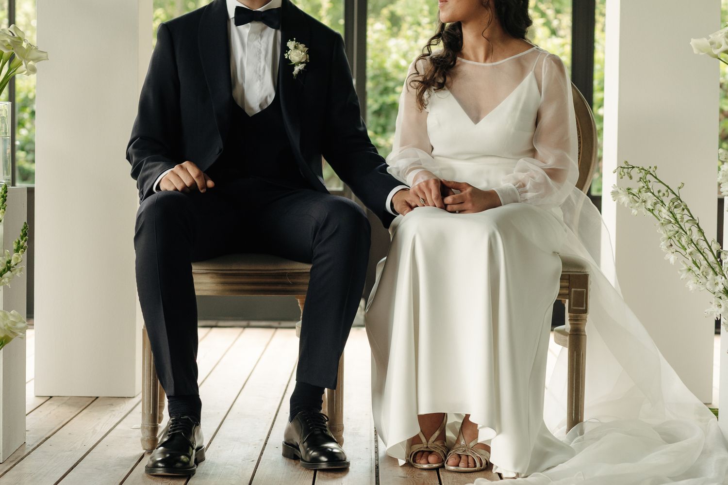 Bride and groom seated side by side in elegant attire during intimate wedding ceremony moment.