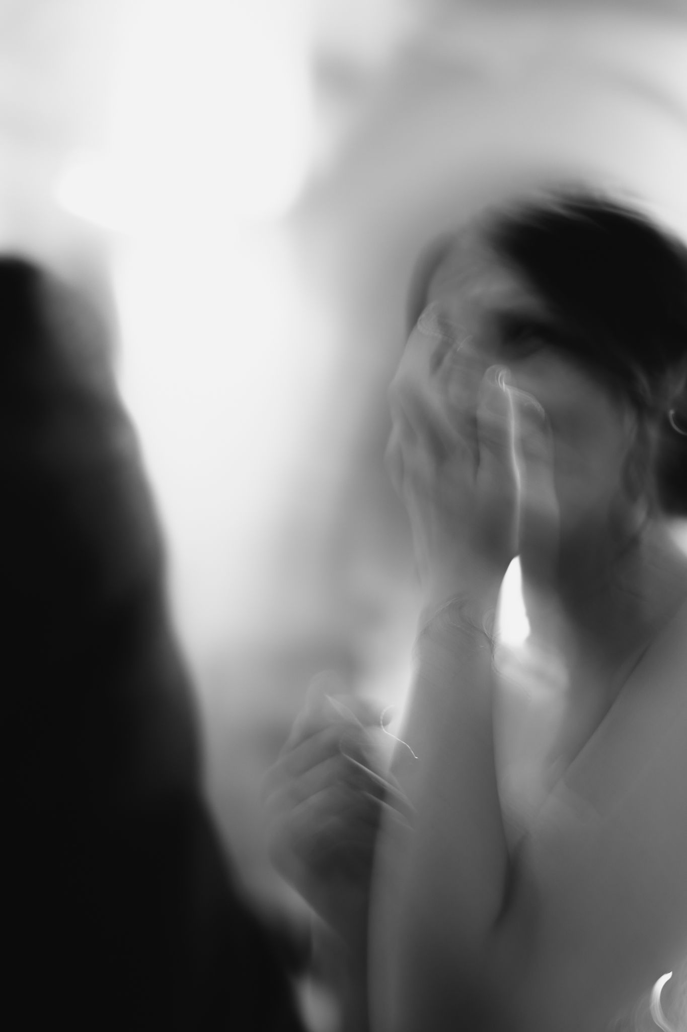 Artistic black and white blurred photo of an emotional bride covering her face with her hands.