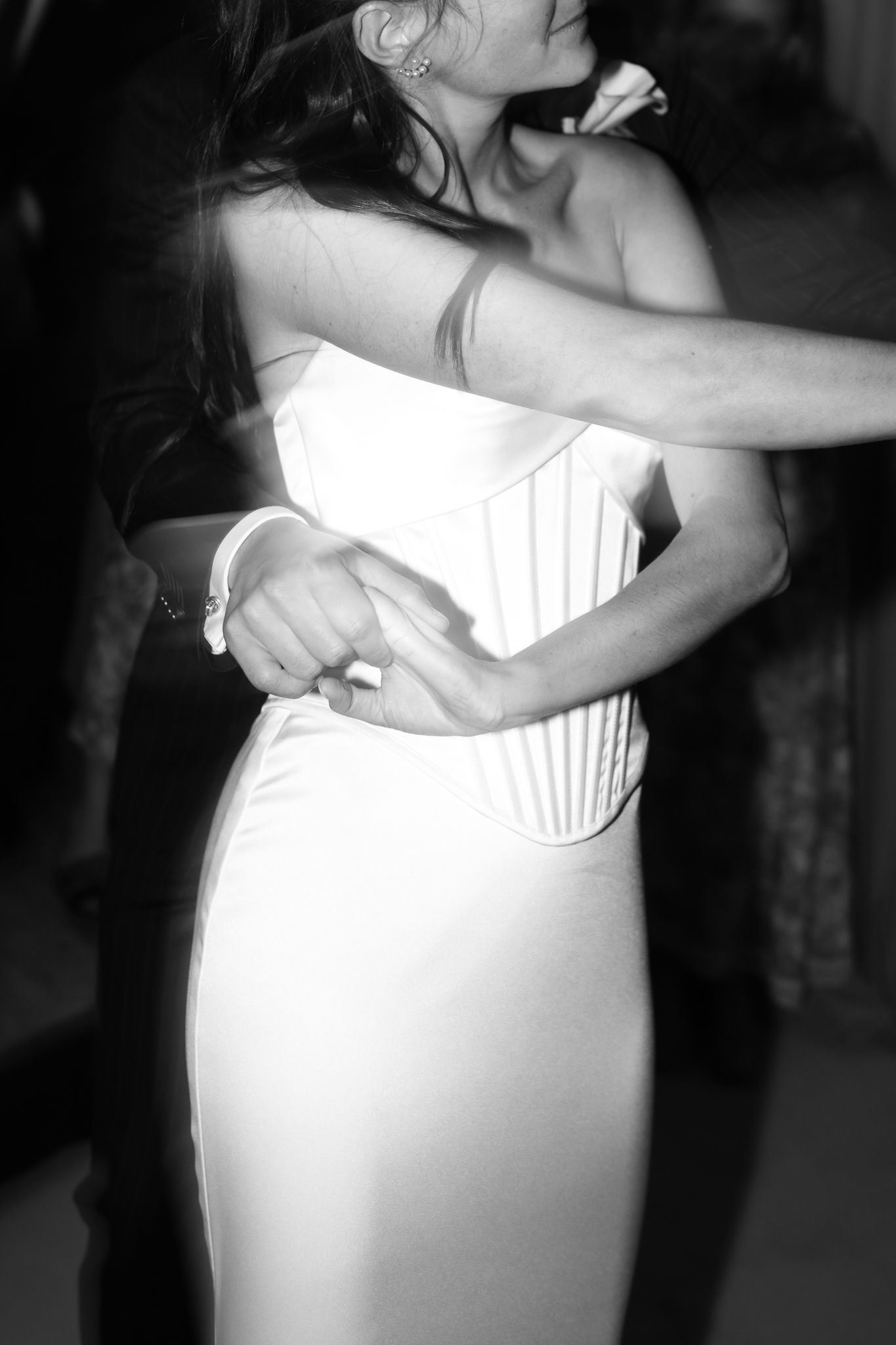 Black and white photo of a bride in a white corset gown sharing a first dance with her partner at a wedding reception.