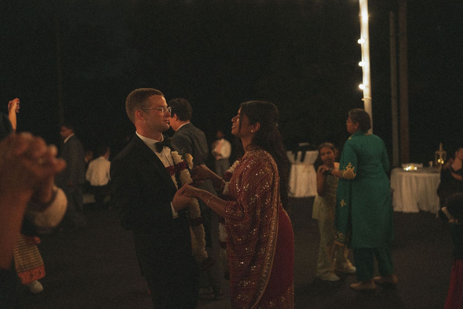 Bride and groom share a romantic first dance outdoors at an evening wedding reception.