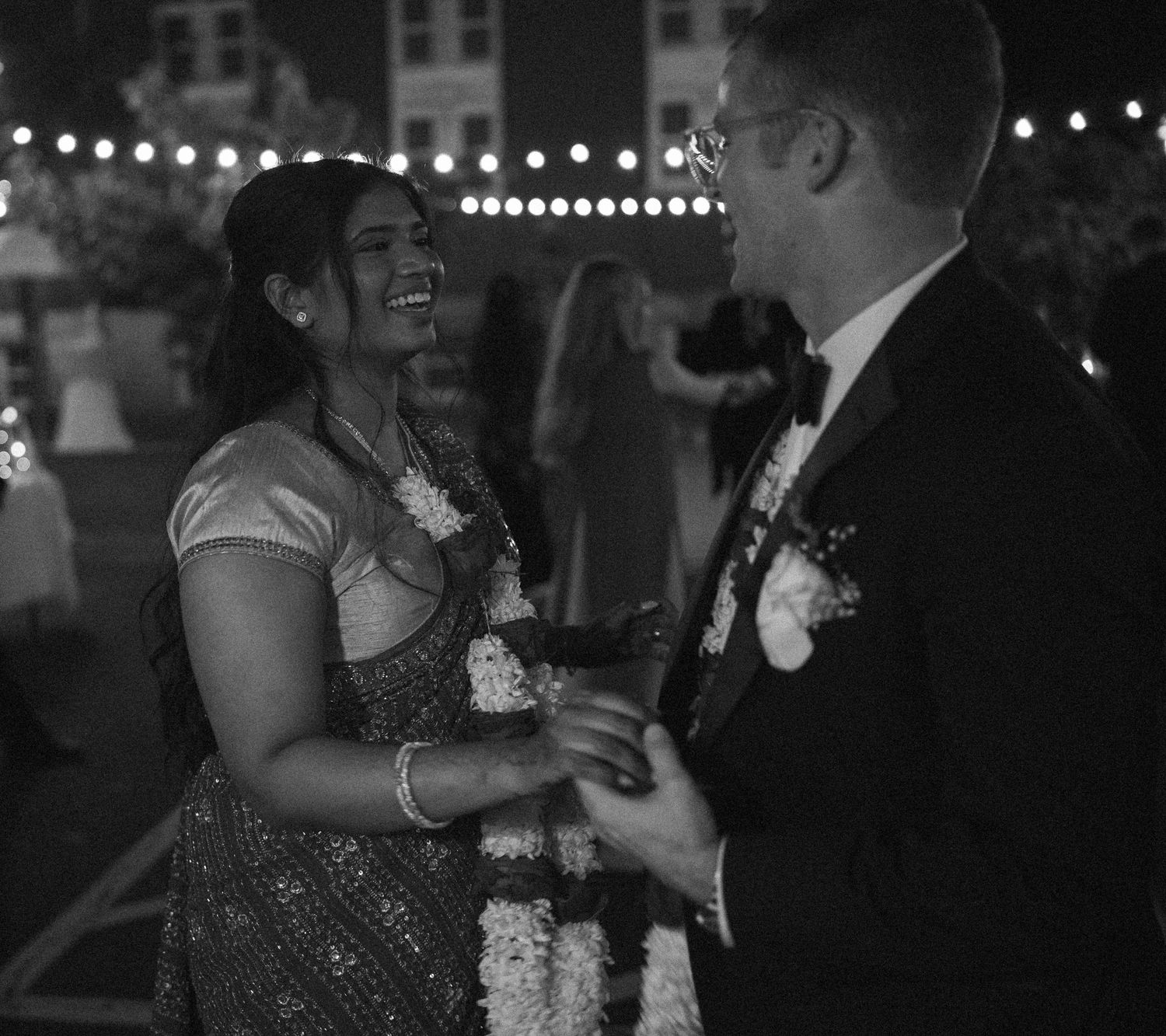 Black and white photo of a bride and groom sharing a joyful moment at an outdoor wedding reception.