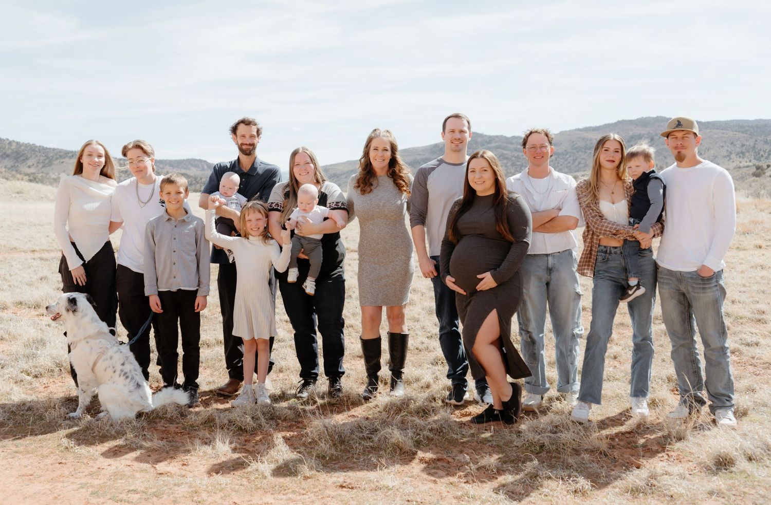Large extended family posing together outdoors in a desert landscape for a professional family portrait photo.