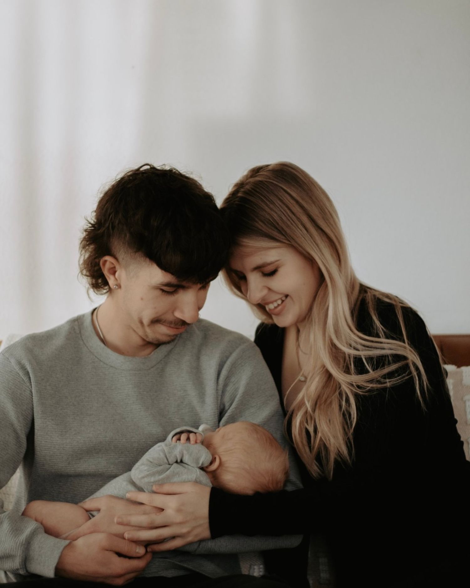 A couple tenderly gazes at their newborn baby, sharing a heartwarming family moment together.
