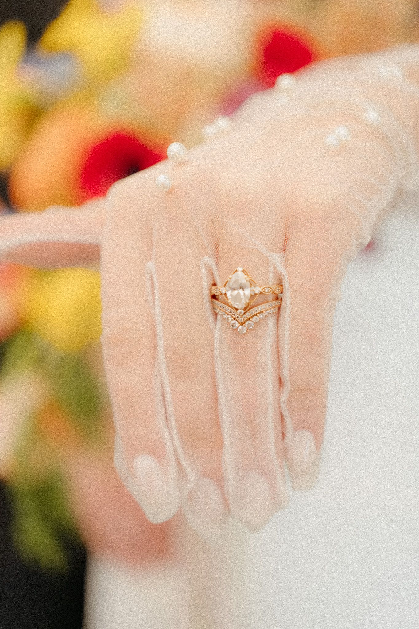 Close-up of marquise diamond engagement ring with chevron band on bride's hand with pearl veil.