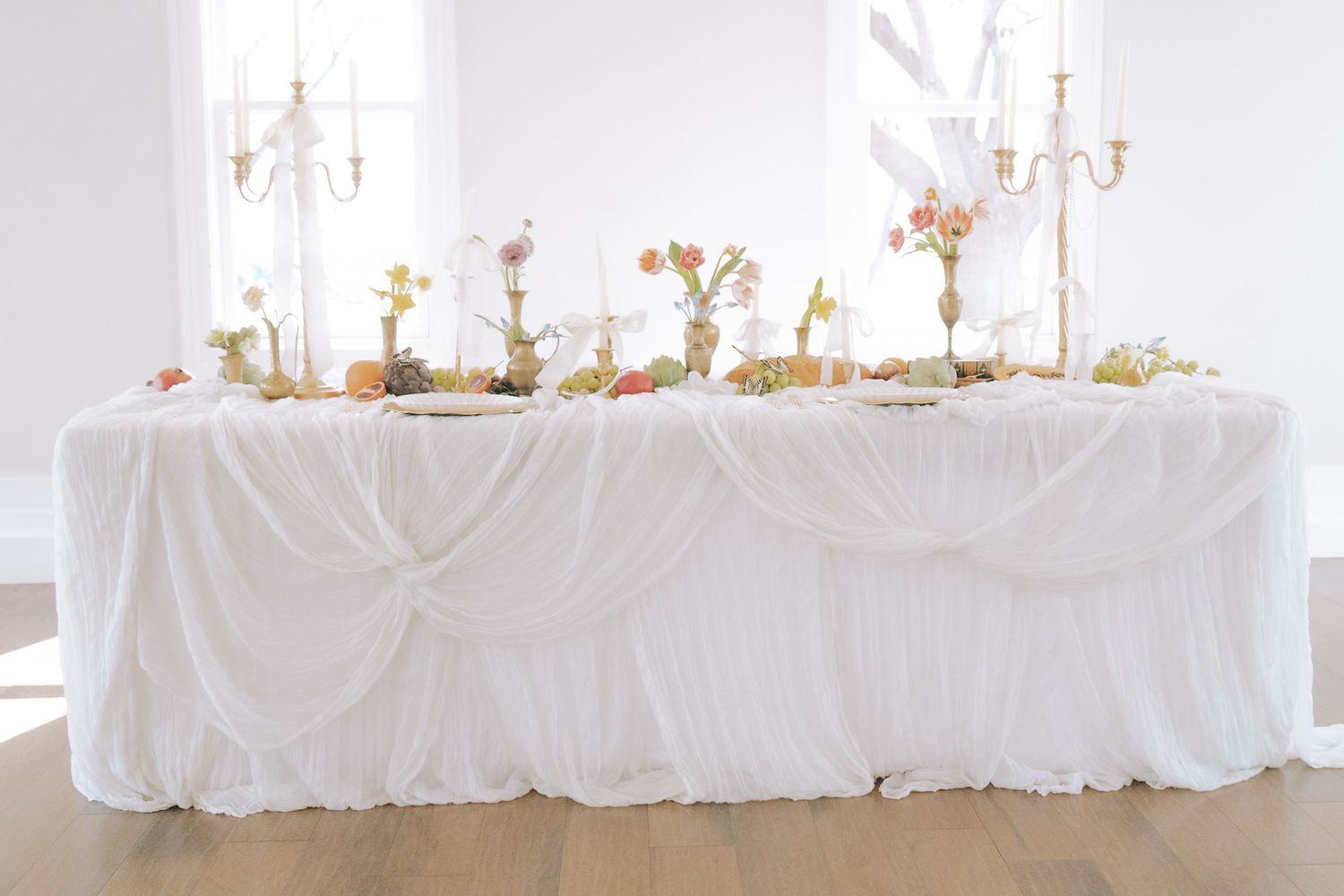 Elegant all-white wedding reception table adorned with colorful floral centerpieces and candelabras.