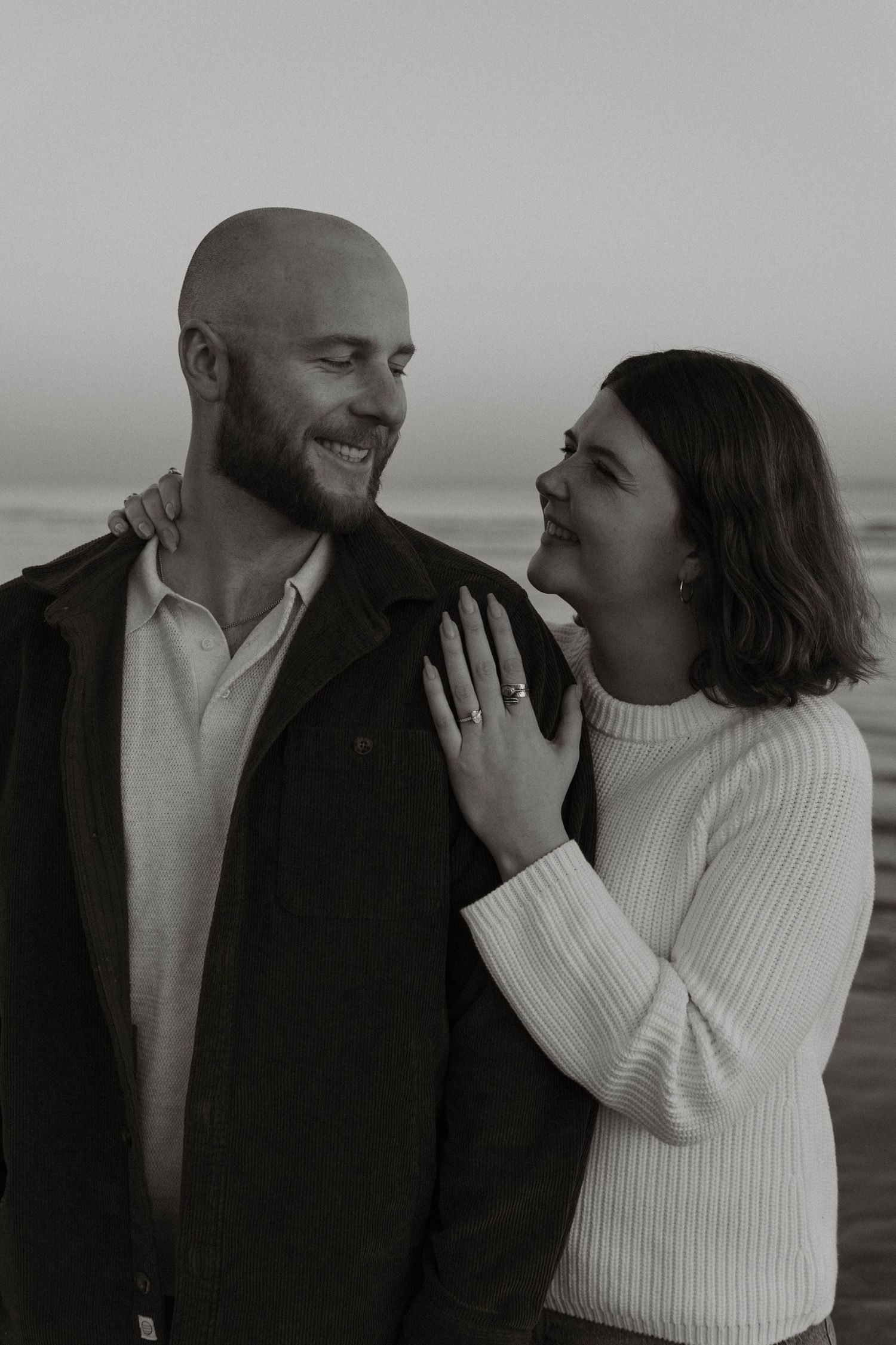 black and white image of happy couple smiling at each other on beach in Charleston, South Carolina