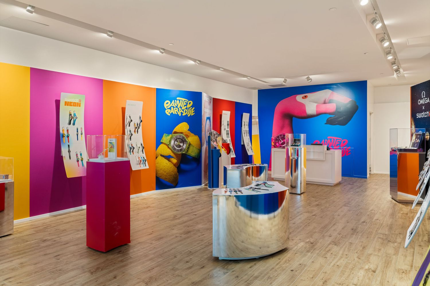 Colorful Swatch store interior with vibrant yellow, pink, and blue walls displaying watch collections on pedestals.