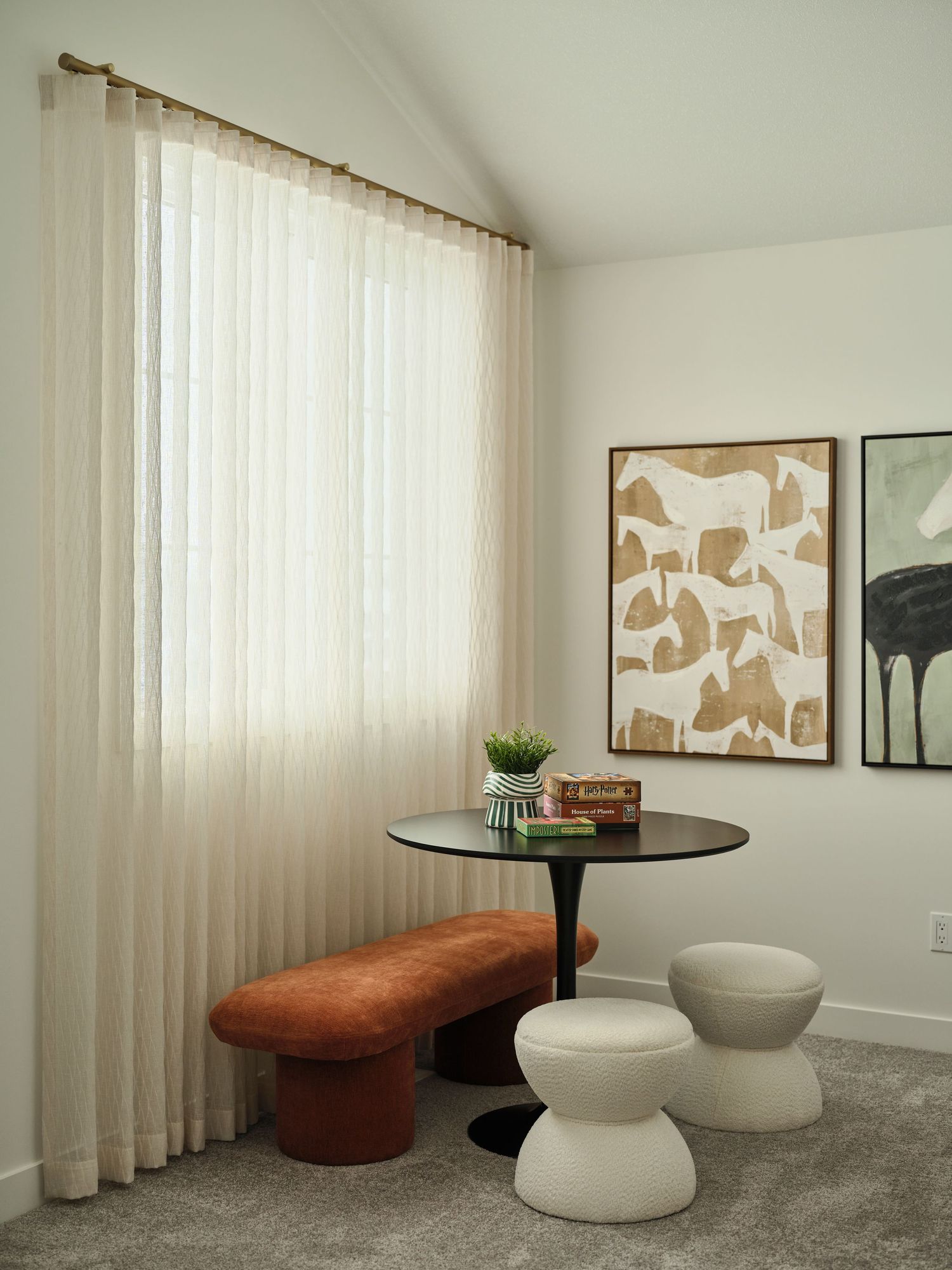 Cozy reading nook with tulip table, velvet bench, mushroom stools, sheer curtains, and abstract wall art.
