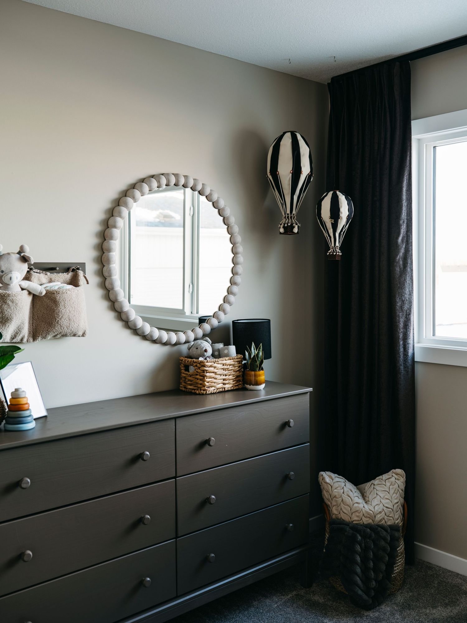 Edmonton interior photography by Ayo Erinle — neutral-toned bedroom with dark dresser and round braided mirror.