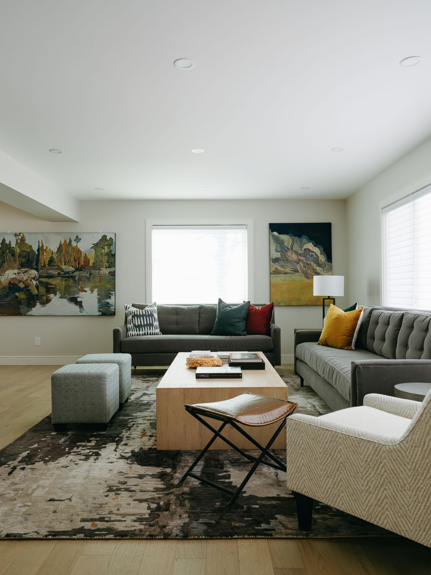Modern living room with gray sofas, abstract art, wood coffee table, and patterned area rug.