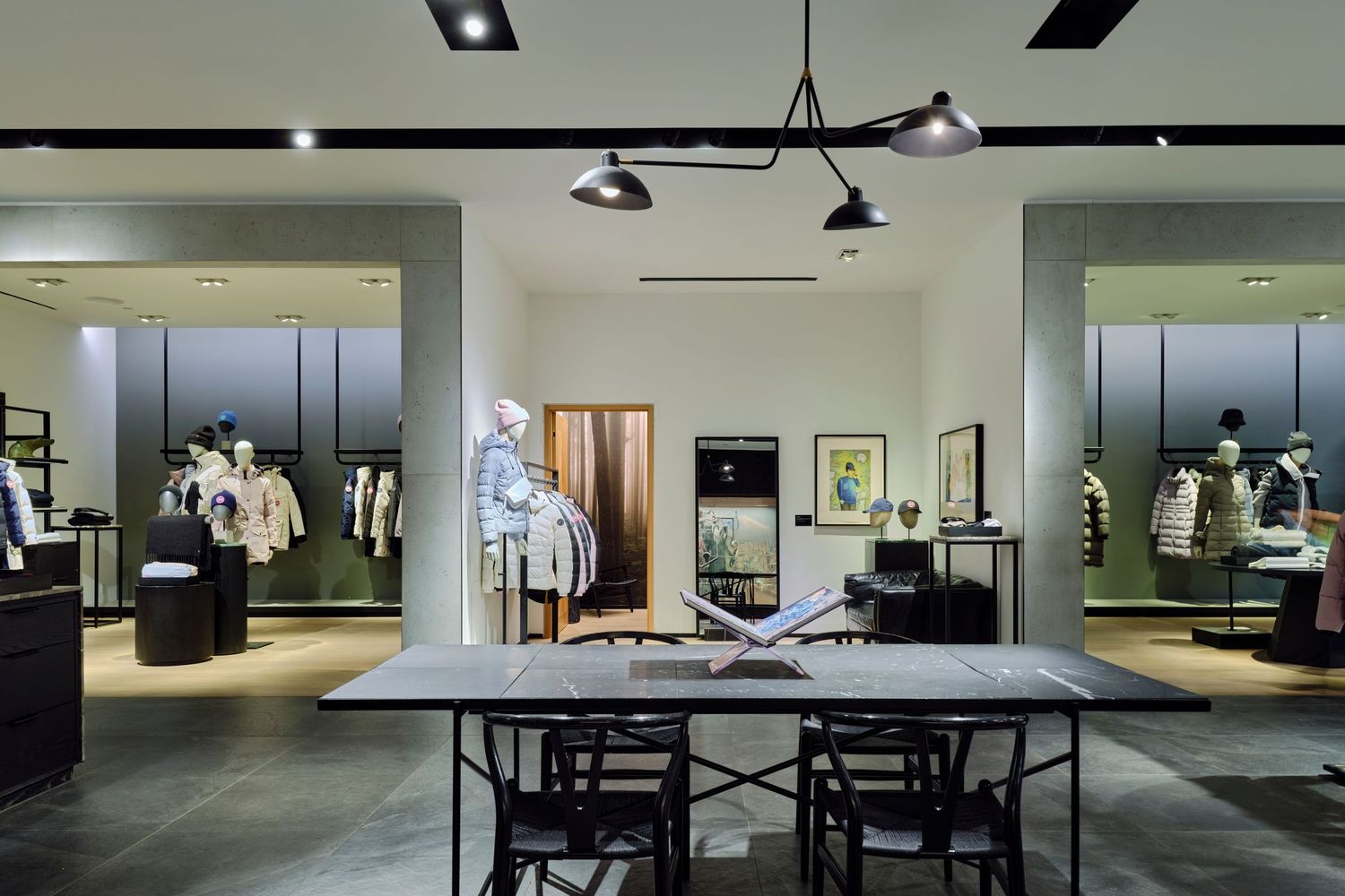 Commercial brand photography by Ayo Erinle — Canada Goose Edmonton store interior with pendant lighting, marble table, and jacket displays.