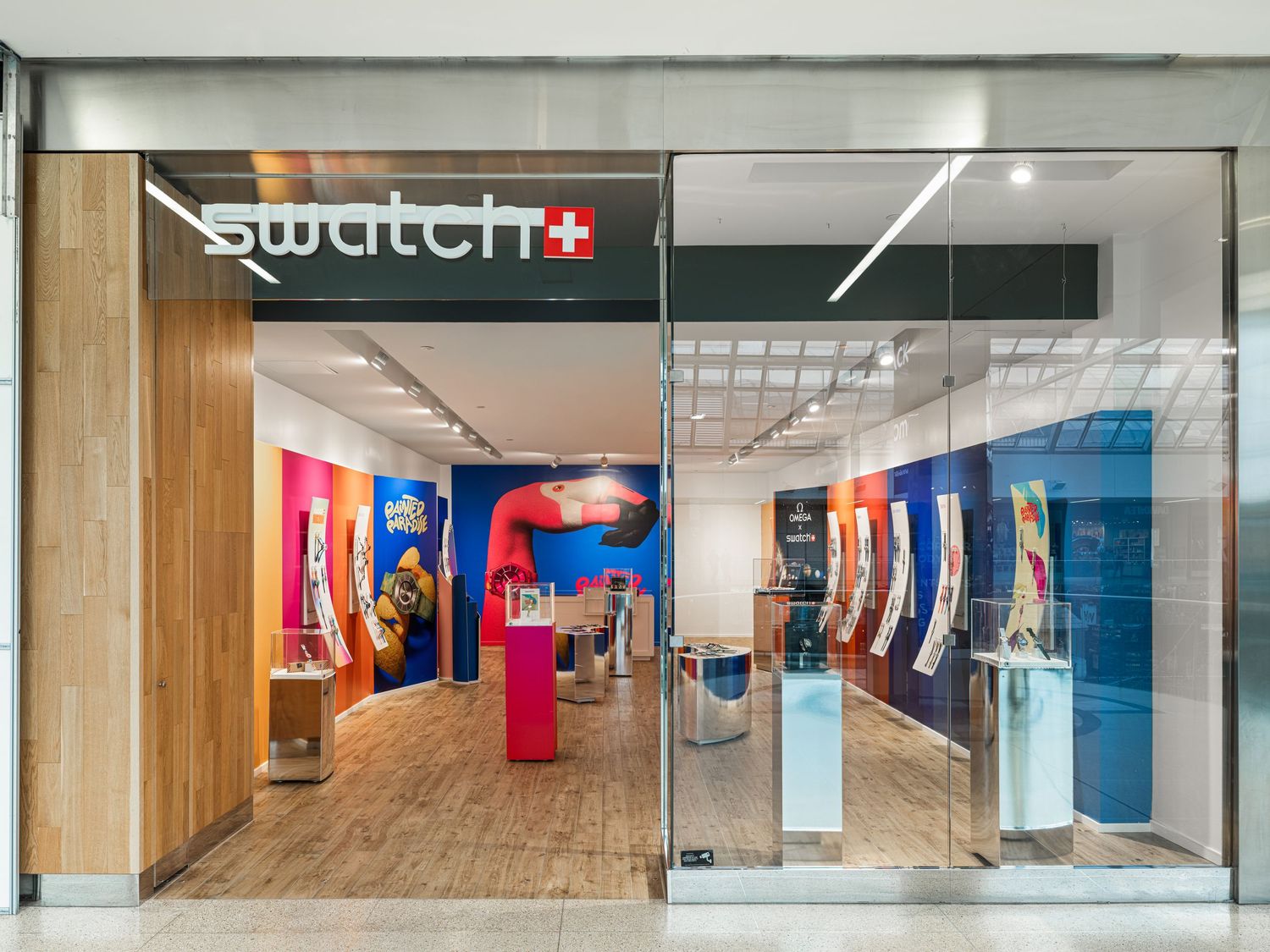 Swatch retail store exterior with colorful displays and watch collections visible through large glass windows.