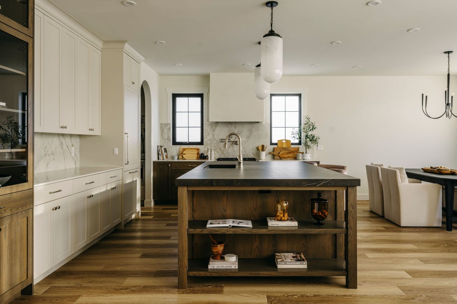 Modern farmhouse kitchen with white cabinets, wood island, dark countertop, pendant lights, and hardwood floors.
