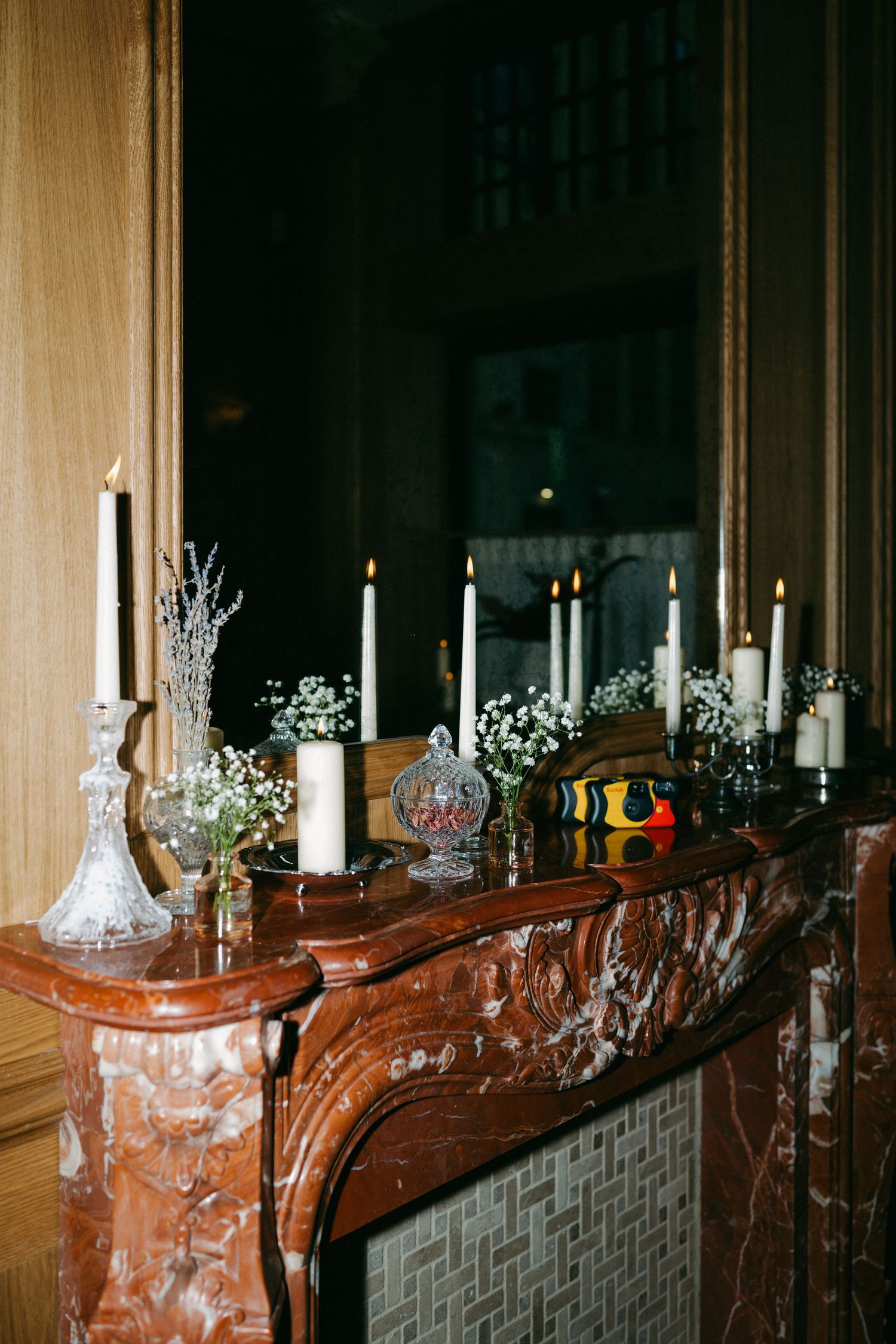 Elegant marble fireplace mantel decorated with white candles and baby's breath flowers.