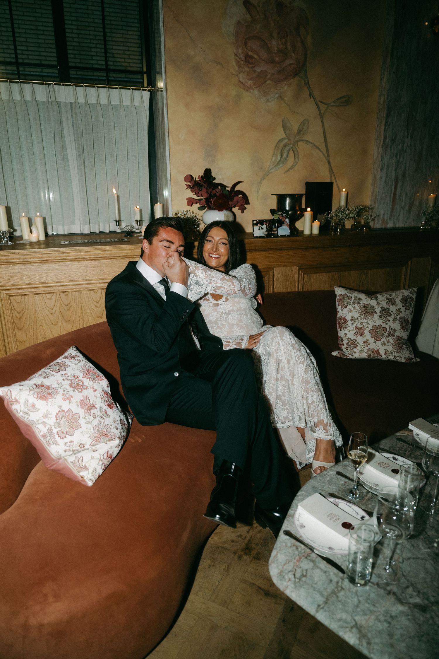 Happy wedding couple relaxing together on velvet sofa in elegantly decorated venue.