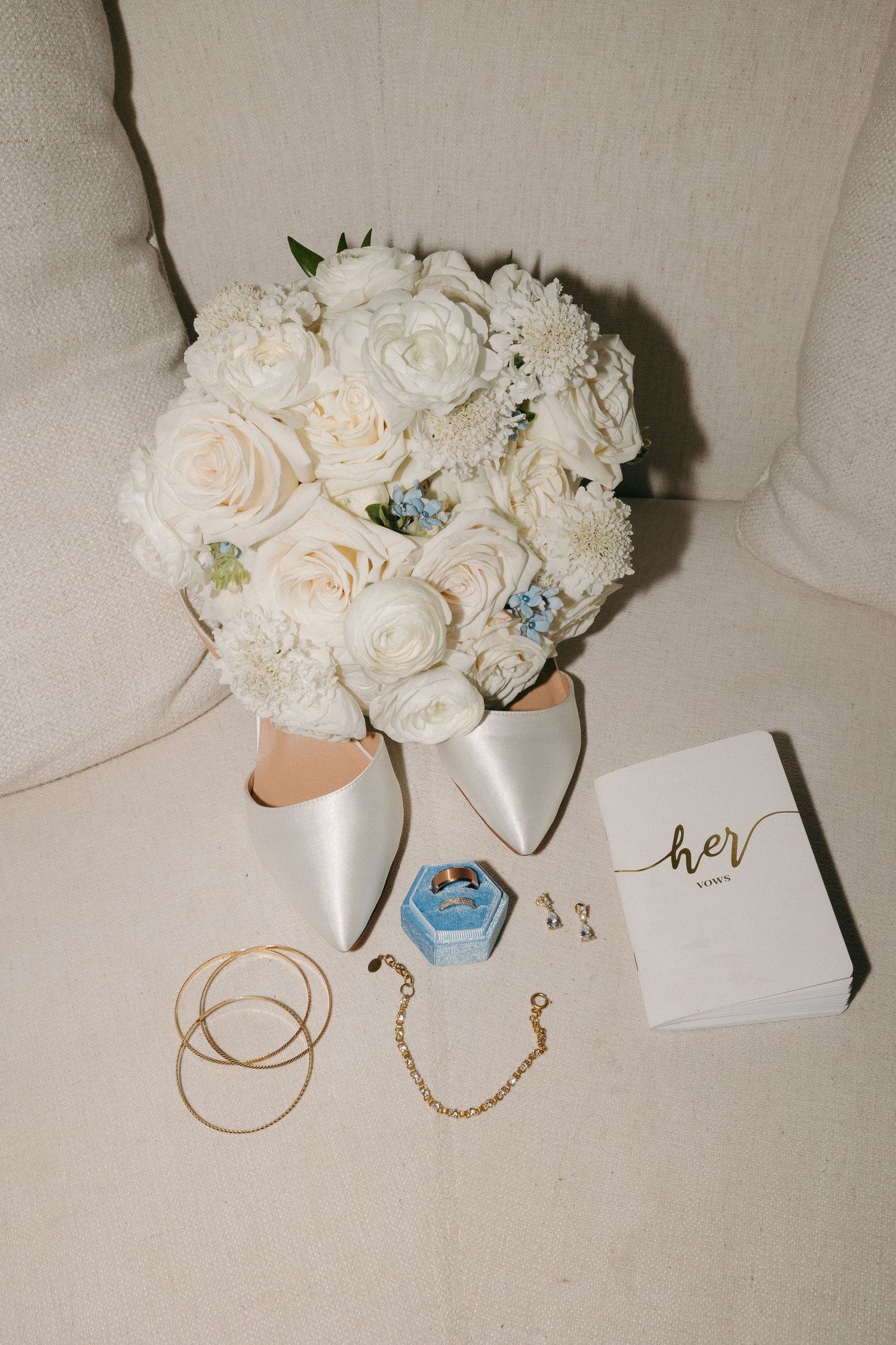 Bridal flat lays featuring white rose bouquet, satin heels, gold jewelry, and vow booklet.