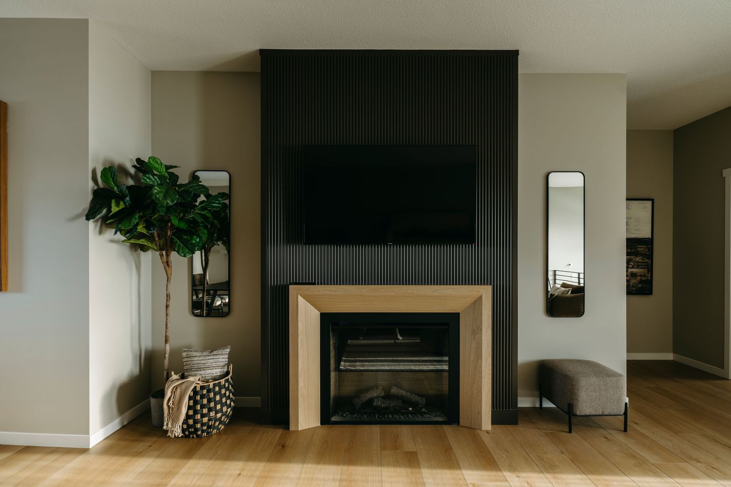 Edmonton interior photography by Ayo Erinle — modern living room with black accent fireplace and light wood flooring.