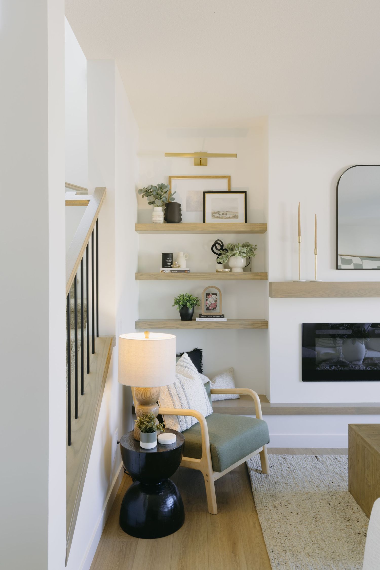 Bright living space with floating wood shelves, accent chair, black side table, and fireplace.