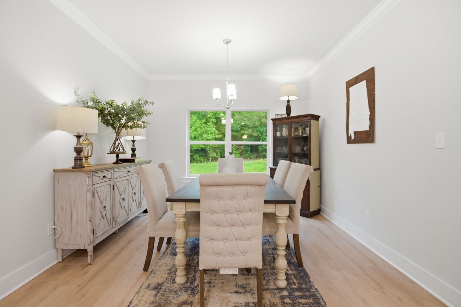 Bright dining room with wood table, upholstered chairs, chandelier, and light hardwood floors.