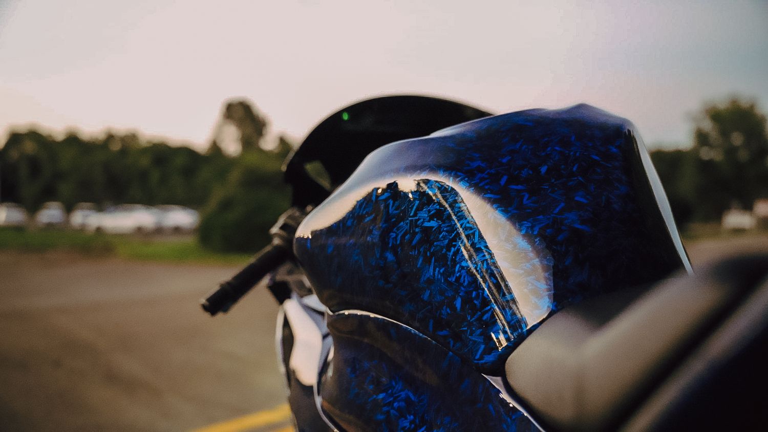 Close-up of a motorcycle fairing with stunning blue marble custom paint, captured at golden hour on a racetrack.