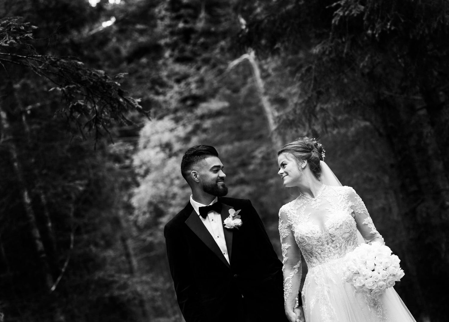 Brudepar som holder hender mens de går og ser hverandre i øynene og smiler i Hægeland i Vennesla